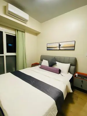 a bedroom with a large white bed and a window at Savvy Suites 2BR Okada View in Manila