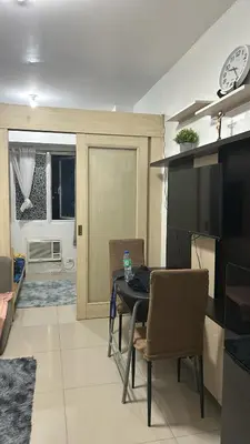 a dining room with a table with chairs and a television at Chays Place in Manila