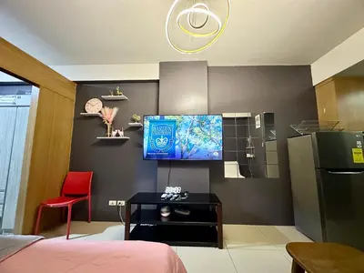 a living room with a tv and a red chair at Kathys Crib Family Suite Room at Shell Residence in Manila