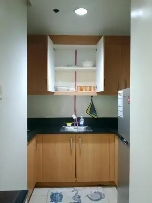 a kitchen with wooden cabinets and a sink at Kys 4 staycation mall of asia in Manila