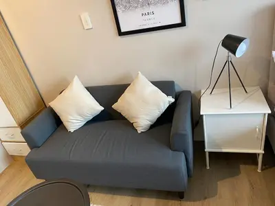 a living room with a blue couch with two pillows at Cosmopolitan Comfort Makati 1 BR Wonder 300MB 2428 Internet in Manila