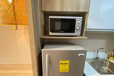 a microwave on a shelf above a refrigerator in a kitchen at Cosmopolitan Comfort Makati 1 BR Wonder 300MB 2428 Internet in Manila