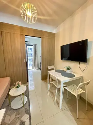 a living room with a table and chairs and a tv at Vanilla Suites Mall of Asia Complex in Manila