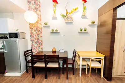 a dining room with a table and chairs and a refrigerator at Canvas & petals Blossoming Art penthouse Gym Swim Park 5716 in Manila