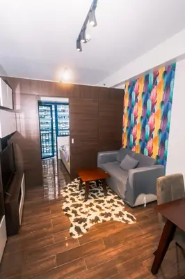 a living room with a couch and a table at Cozy Peacock hideaway Stylish Makati Condo 300 Mbps Gym Swim Park in Manila