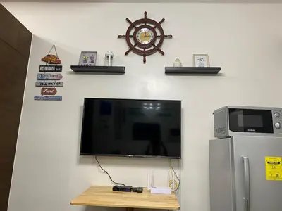 a flat screen tv on a wall next to a refrigerator at Cruise Ship Condo Escape Makati 300 Mbps Gym Swim Park 2271 in Manila
