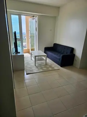 a living room with a blue couch and a table at 3BR at The Rochester in Manila