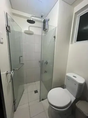 a bathroom with a toilet and a glass shower at 3BR at The Rochester in Manila