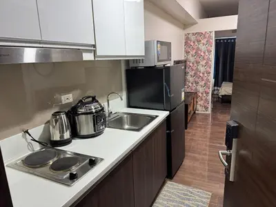 a small kitchen with a sink and a refrigerator at Galloping Suite Executive Makati Suite Gym Swim Park 300 Mbps in Manila
