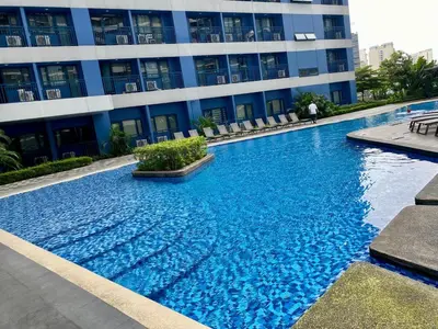 a large blue swimming pool in front of a building at Galloping Suite Executive Makati Suite Gym Swim Park 300 Mbps in Manila