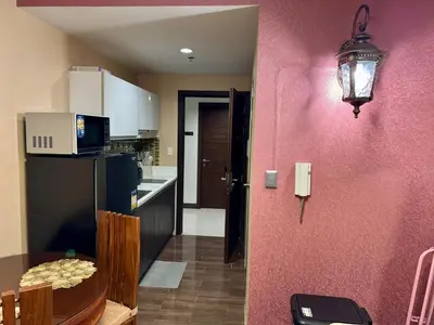 a kitchen with a table and a pink wall at Heavenly holiday Italian Rome Air Makati Gym Swim Park 300 in Manila