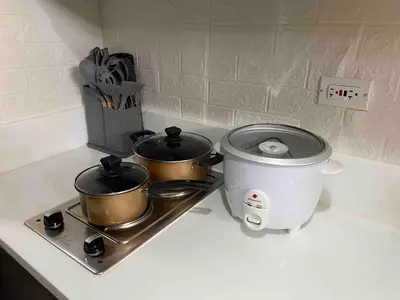 a counter with two pots on a stove with a toaster at Jazz Air Rooftop Penthouse Bar Gym Swim Park 300 Mbps Air 4034 in Manila