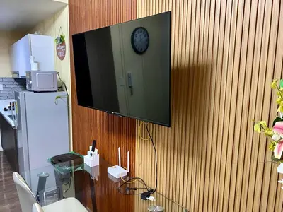 a tv hanging on a wall with a clock on it at Makati Ayala luxury Stylish Uncle Sam condo Gym Swim Park 300 Mb 2641 in Manila