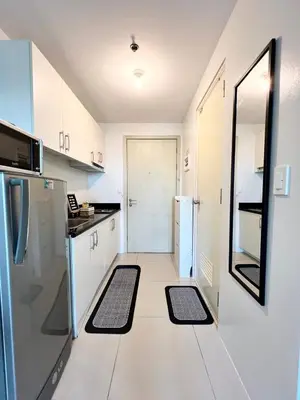 a kitchen with white cabinets and black and white appliances at High Rise Haven in Makati with Balcony and View in Manila