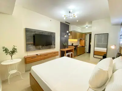 a bedroom with a bed and a flat screen tv at cozy studio unit near airport in Manila