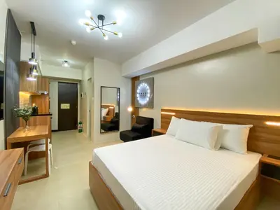 a hotel room with a bed and a desk at cozy studio unit near airport in Manila