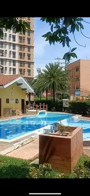a large swimming pool with a large building in the background at cozy studio unit near airport in Manila