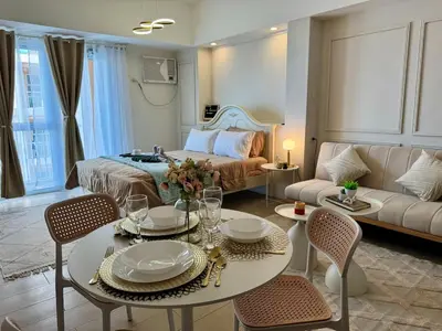 a living room with a bed and a table and chairs at Chic Staycation with Balcony,few step in venice mall in Manila