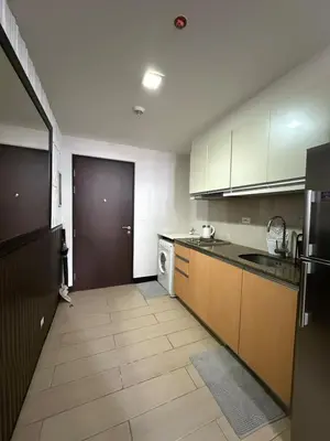 a kitchen with white cabinets and a black refrigerator at Luxurious Studio Unit in Salcedo in Manila