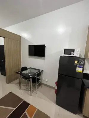 a room with a table and a black refrigerator at Shore Residence 1 Bedroom Staycation in Manila