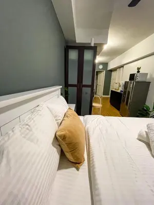 a bedroom with a white bed with a yellow pillow at Studio condo near Pobla Makati in Manila