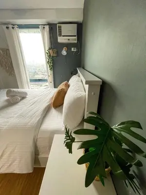 a bedroom with a bed with a plant and a window at Studio condo near Pobla Makati in Manila