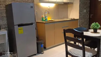 a kitchen with a refrigerator and a table with a chair at Nethcondo in Manila