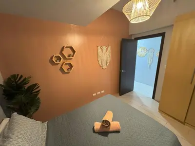 a room with a bed with a hat on it at Cozy 3 Bedroom in Uptown Parksuites - Near Mall, Restaurants and Supermarket in Manila