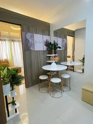 two tables and stools in a room with plants at Field Residences Condo Hotel in Manila