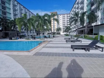 a pool with benches and palm trees and buildings at Field Residences Condo Hotel in Manila