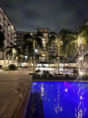 a large swimming pool in a city at night at Field Residences Condo Hotel in Manila