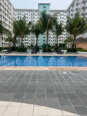 a swimming pool with palm trees and buildings at Field Residences Condo Hotel in Manila