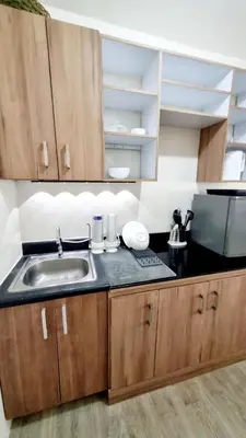 a kitchen with a sink and wooden cabinets at Joms Minimalist Crib Nuvali in Calamba