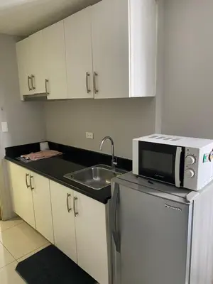 a kitchen with a sink and a microwave at jazz residence in Manila