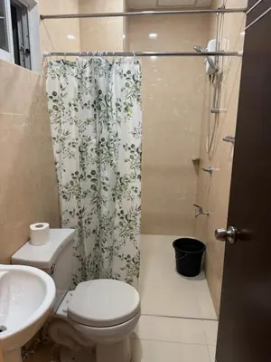a bathroom with a toilet and a shower curtain at Casa Maria by Juemarst Suites in Manila