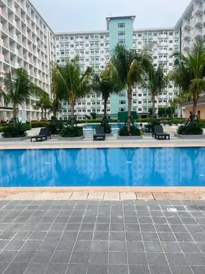 a swimming pool with palm trees in front of a building at Field Residences Condo Hotel in Manila