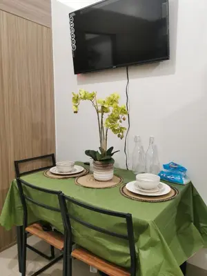 a green table with chairs and a television on a wall at Shore 2 Residences in Manila