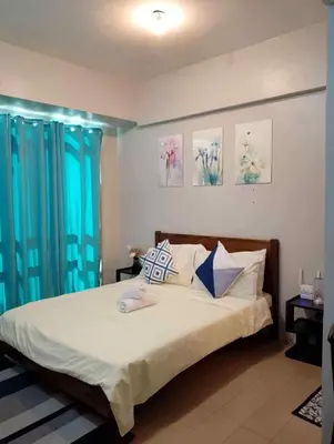 a bedroom with a large bed with blue curtains at Happy stay Condotel near NAIA terminal 3 in Manila