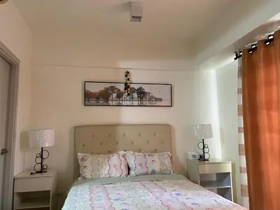 a bedroom with a bed with two night stands and two lamps at Happy stay Condotel near NAIA terminal 3 in Manila