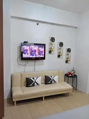 a living room with a couch and a tv on a wall at Happy stay Condotel near NAIA terminal 3 in Manila