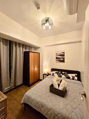 a bedroom with a large bed with a chair at SG Urban Staycation in Manila