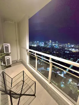 a chair on a balcony with a view of the city at SG Urban Staycation in Manila