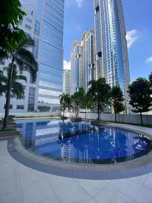 a large pool in a city with tall buildings at Relaxing shining sunrise in Manila