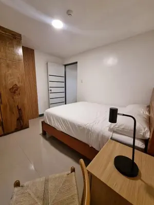 a bedroom with a bed and a table with a lamp at Flat 35, Unit 3C in Manila