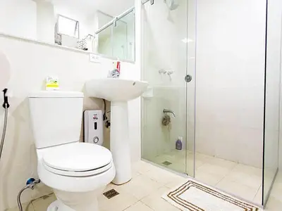 a white bathroom with a toilet and a shower at Avant Apartments at The Fort in Manila