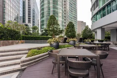 a patio with tables and chairs and tall buildings at Avant Apartments at The Fort in Manila