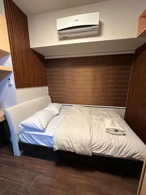 a bedroom with a bed with a wooden wall at 1BR Air Residences condo, Ayala Ave, Makati in Manila
