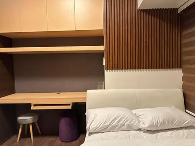 a bedroom with a bed and a wooden desk at 1BR Air Residences condo, Ayala Ave, Makati in Manila