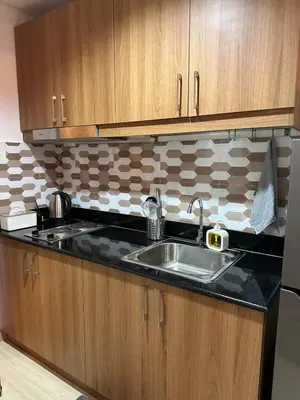 a kitchen with a sink and wooden cabinets at 1BR Ayala Makati Apartment at Lush Residences in Manila