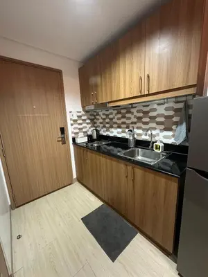 a kitchen with wooden cabinets and a sink and a refrigerator at 1BR Ayala Makati Apartment at Lush Residences in Manila